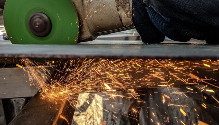 Close-up of a worker using a grinder, creating sparks in a metal workshop environment.